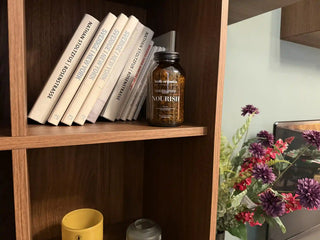A jar of loose leaf tea by Welb Organics on a shelf with books next to a flower pot
