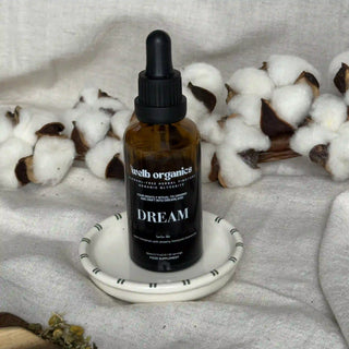 Brown glass bottle with dropper labeled 'welb organics' on a white surface with cotton in the background